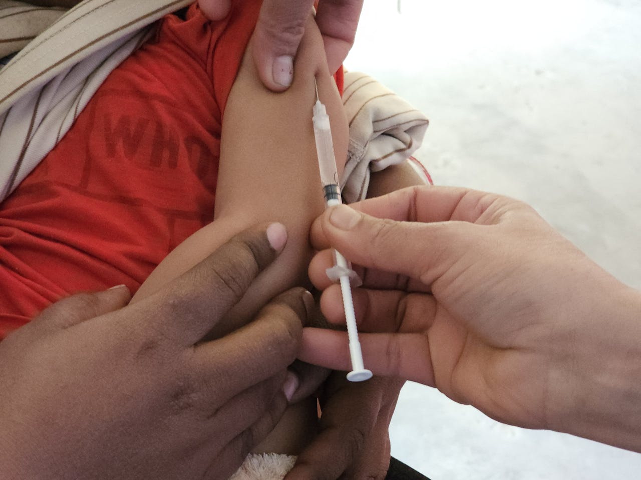 A child getting a vaccination shot administered by a healthcare professional indoors.