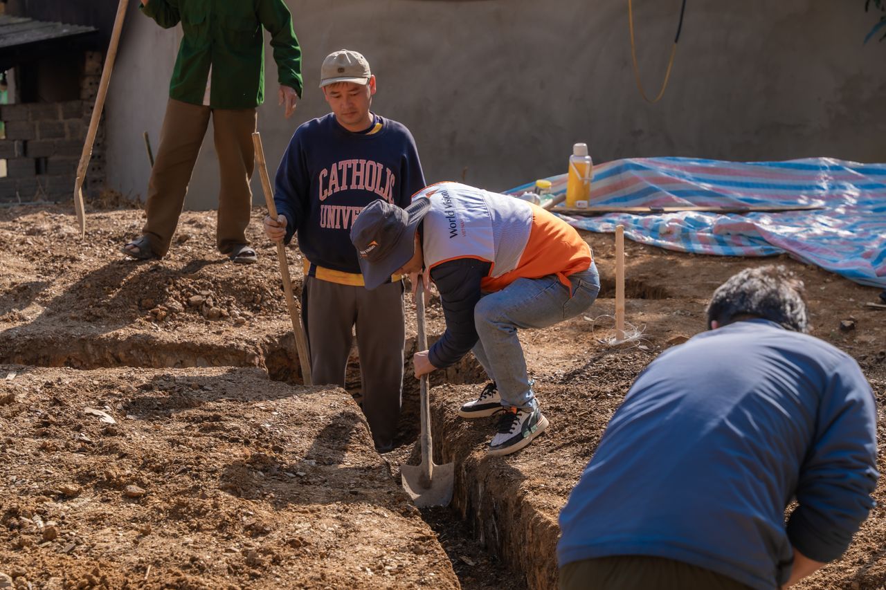hero-img-02 Volunteers working together to dig a trench at a construction site in daylight.