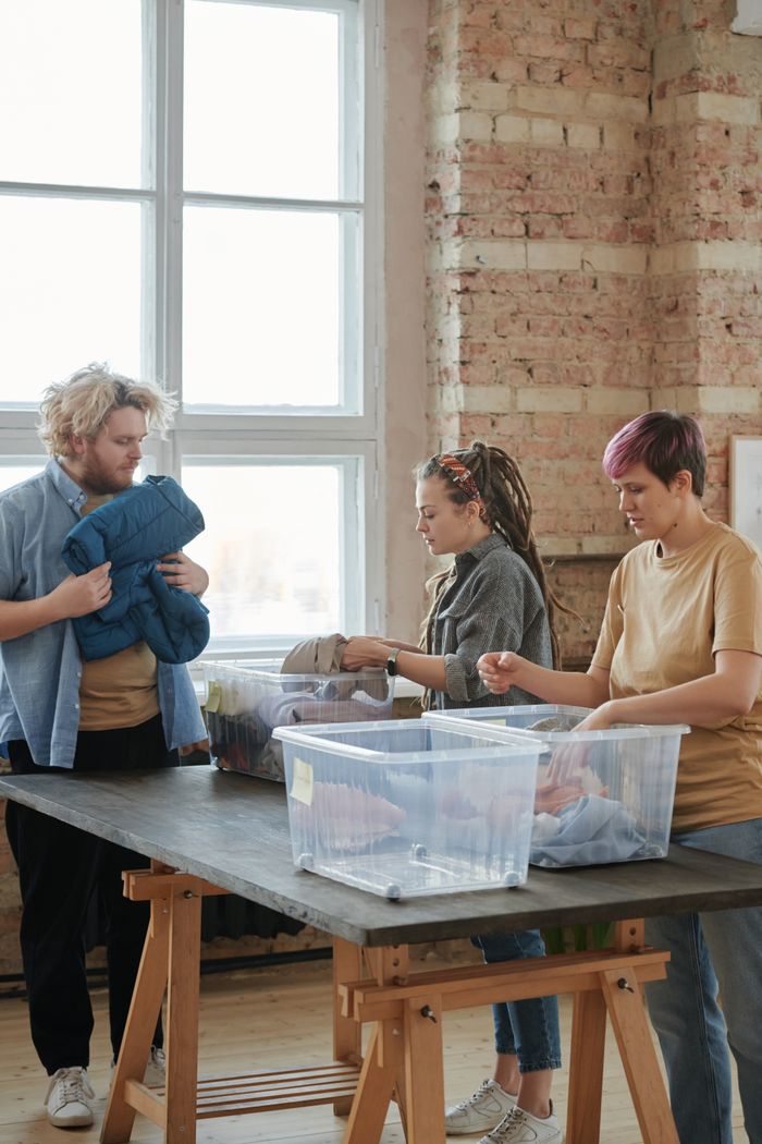 The Art of Drawing Readers In: Your attractive post title goes here Three volunteers sorting clothes indoors. Engaged in organizing for charity, teamwork, and community service.